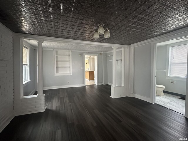 interior space featuring an ornate ceiling, ornamental molding, wood finished floors, ornate columns, and built in shelves