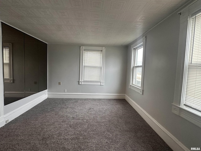 carpeted spare room featuring baseboards