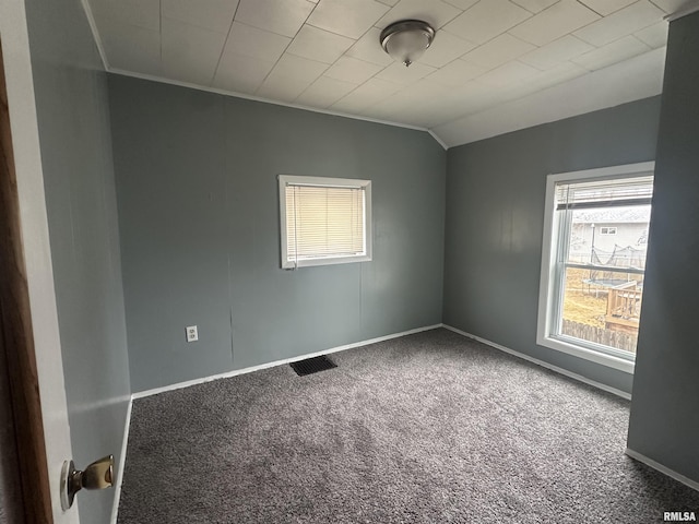 carpeted empty room featuring vaulted ceiling, ornamental molding, visible vents, and baseboards