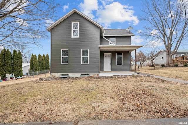 traditional-style home featuring a front yard, covered porch, and fence