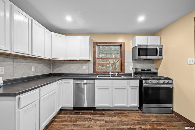 kitchen with appliances with stainless steel finishes, dark countertops, a sink, and wood tiled floor