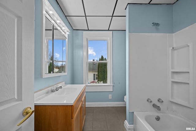 bathroom with shower / bathtub combination, vanity, a drop ceiling, baseboards, and tile patterned floors