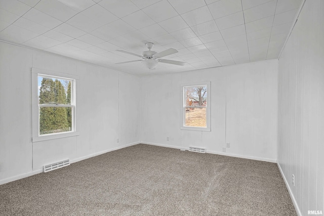 carpeted empty room with plenty of natural light, visible vents, and a ceiling fan