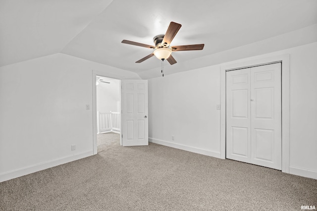 unfurnished bedroom featuring lofted ceiling, a closet, carpet flooring, and baseboards