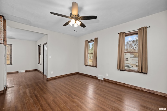 empty room featuring dark wood-style floors, baseboards, and visible vents