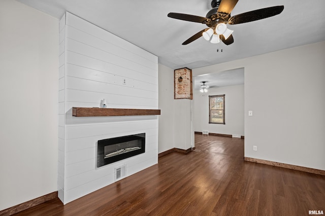 unfurnished living room with a fireplace, wood finished floors, visible vents, and baseboards