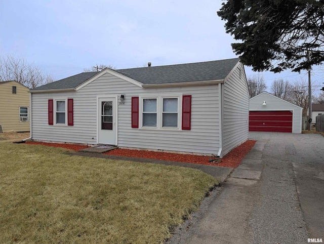 view of front of home featuring a shingled roof, an outbuilding, a garage, and a front lawn