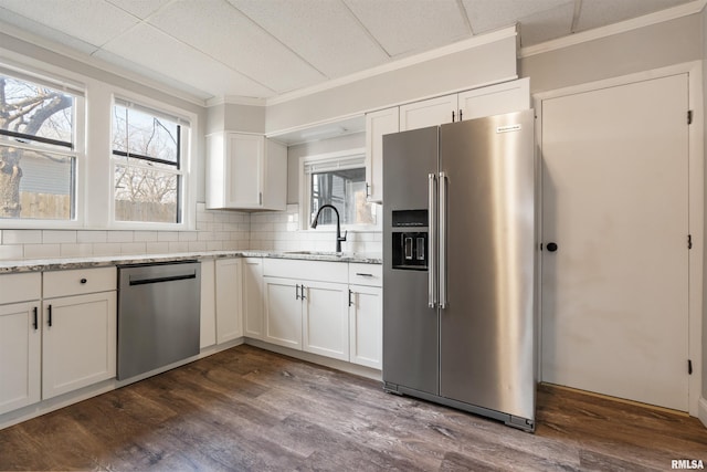 kitchen with dark wood-style flooring, a sink, white cabinetry, appliances with stainless steel finishes, and decorative backsplash