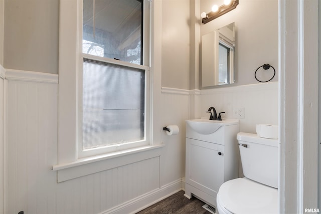 bathroom featuring visible vents, toilet, a wainscoted wall, wood finished floors, and vanity