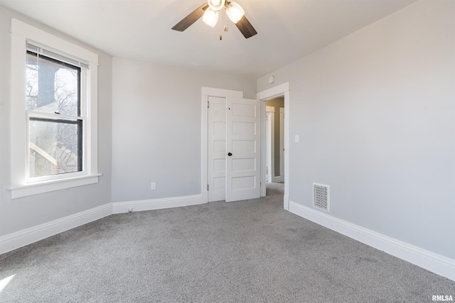 carpeted spare room with a ceiling fan, visible vents, and baseboards