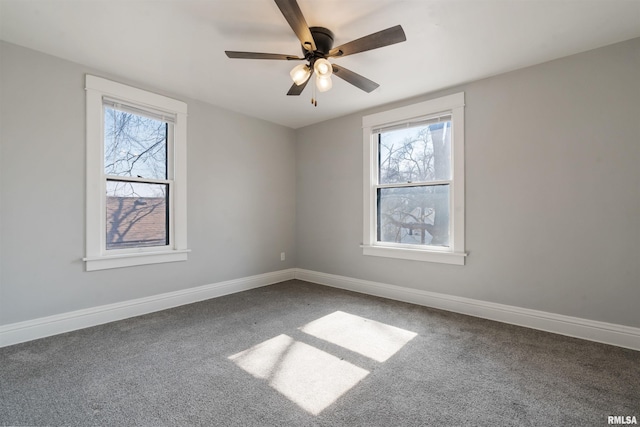 carpeted empty room with ceiling fan, baseboards, and a wealth of natural light