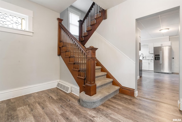 stairway featuring visible vents, a wealth of natural light, and wood finished floors