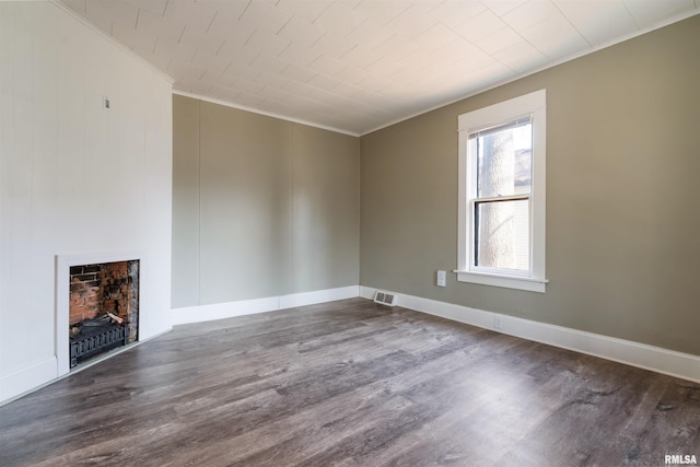 unfurnished living room with baseboards, visible vents, wood finished floors, crown molding, and a fireplace