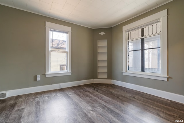 unfurnished room featuring ornamental molding, dark wood-style flooring, visible vents, and baseboards