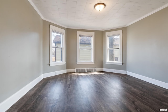 empty room with baseboards, visible vents, dark wood finished floors, and crown molding