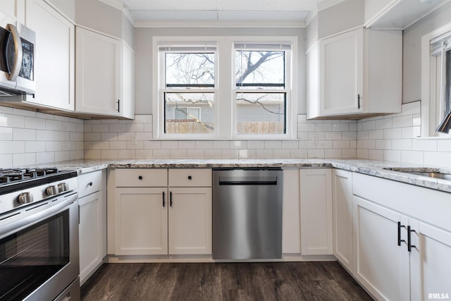 kitchen featuring stainless steel appliances, ornamental molding, dark wood finished floors, and white cabinets