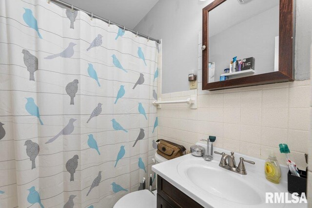 bathroom featuring toilet, vanity, tile walls, and a shower with curtain