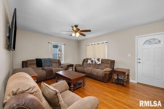 living area with ceiling fan, light wood finished floors, and baseboards