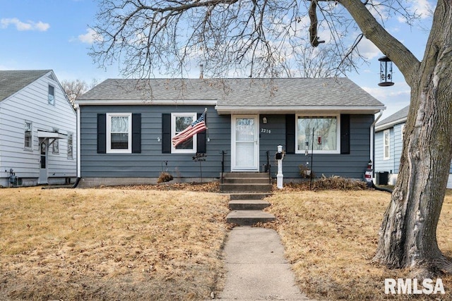 view of front of home with roof with shingles and a front yard