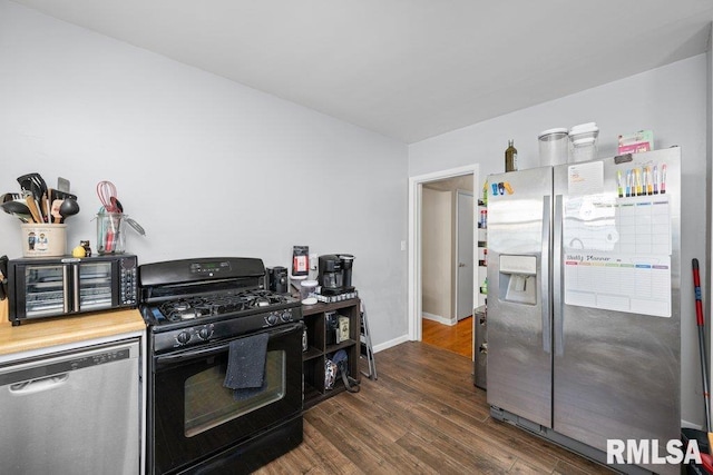 kitchen with appliances with stainless steel finishes, dark wood-type flooring, and baseboards