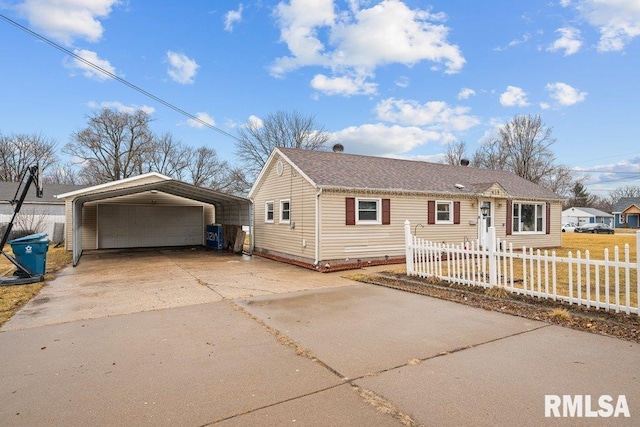 view of front facade featuring driveway, a fenced front yard, an outdoor structure, and a detached carport