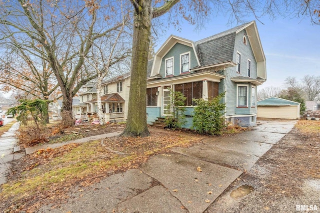 view of front of property with a garage, entry steps, a shingled roof, a gambrel roof, and a sunroom