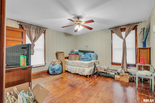 bedroom with a ceiling fan, wood-type flooring, and wallpapered walls