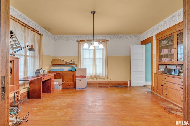 dining area with wallpapered walls, baseboards, and wood finished floors