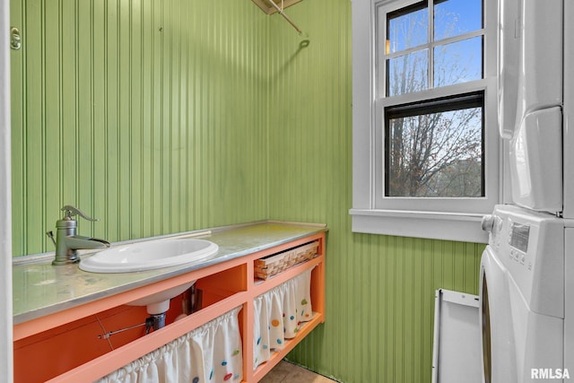 bathroom with stacked washer and dryer and a sink