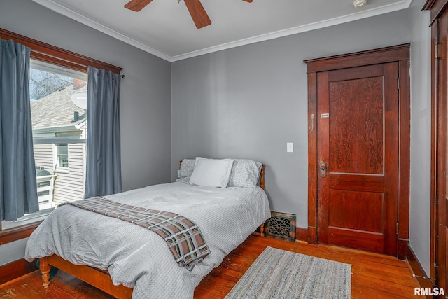 bedroom with a ceiling fan, baseboards, ornamental molding, and wood finished floors