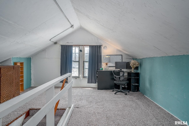 unfurnished office featuring carpet flooring, vaulted ceiling, and a textured ceiling