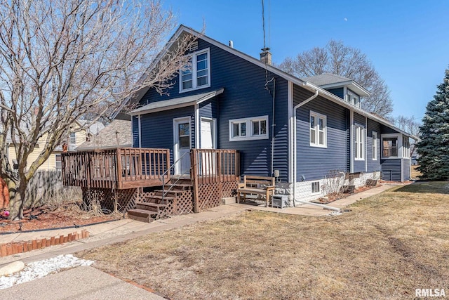 view of front of house with a front yard, a chimney, and a wooden deck