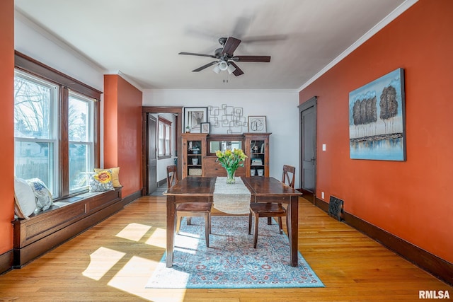 dining area with visible vents, a ceiling fan, baseboards, ornamental molding, and light wood-type flooring