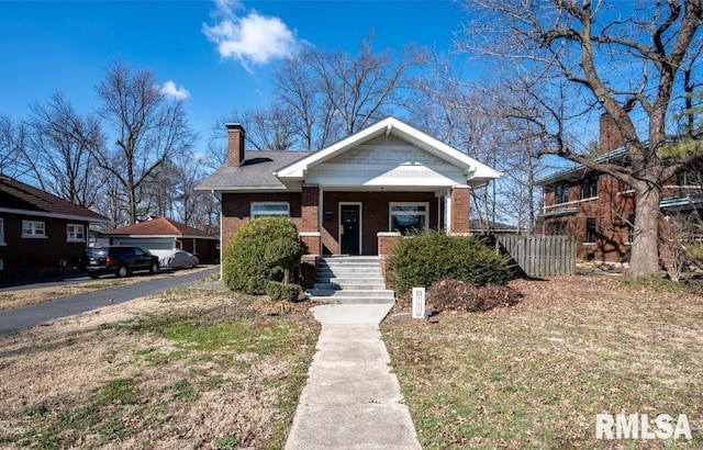 bungalow featuring a porch, brick siding, and a chimney