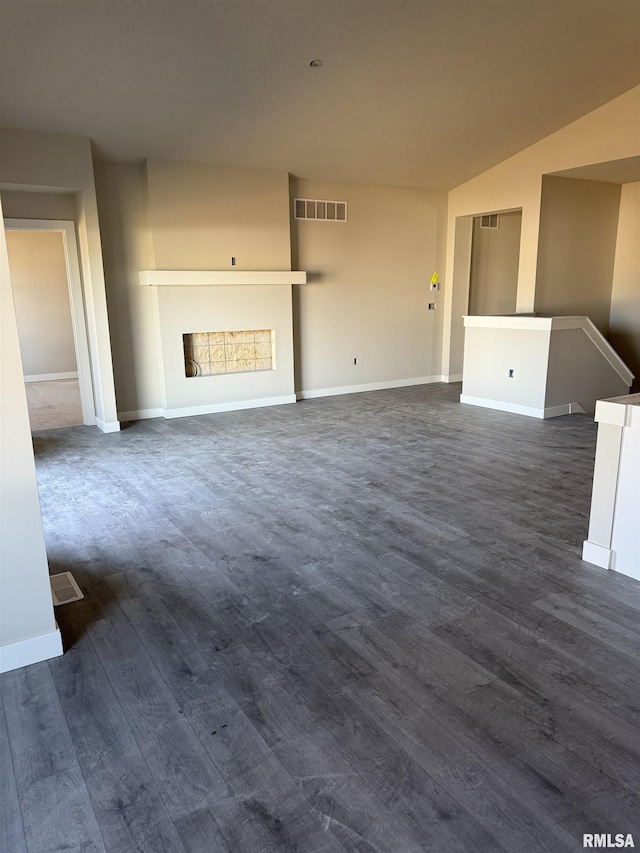 unfurnished living room with visible vents, baseboards, a fireplace, and dark wood-style flooring