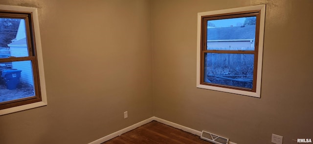 empty room featuring dark wood finished floors, visible vents, and baseboards