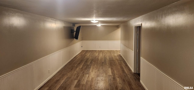 hall with a wainscoted wall and dark wood-type flooring