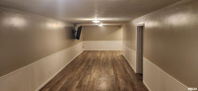 hall featuring a wainscoted wall and dark wood-type flooring