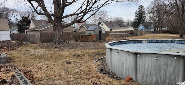 view of swimming pool with a fenced in pool, a fenced backyard, an outdoor structure, and a storage unit