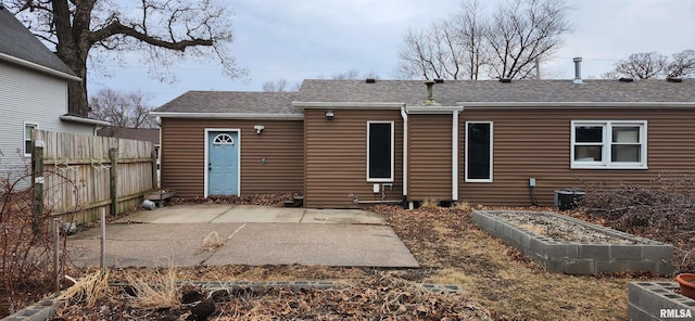 rear view of property featuring a vegetable garden, a patio area, fence, and roof with shingles