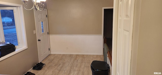 entrance foyer featuring wainscoting, light wood finished floors, and an inviting chandelier