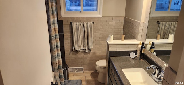 full bathroom featuring tile patterned flooring, toilet, vanity, visible vents, and tile walls