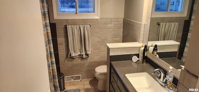 full bathroom with tile walls, visible vents, toilet, vanity, and tile patterned floors