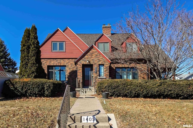 view of front of house with a front yard, brick siding, and a chimney