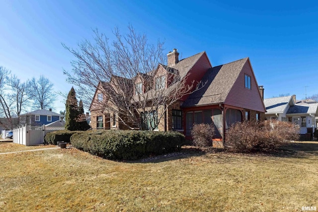 view of front of house featuring brick siding, a chimney, and a front yard