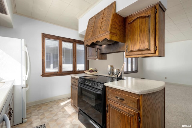 kitchen featuring black electric range, baseboards, light countertops, and freestanding refrigerator