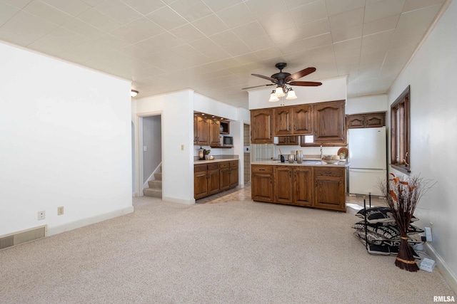 kitchen featuring ceiling fan, light colored carpet, visible vents, light countertops, and freestanding refrigerator