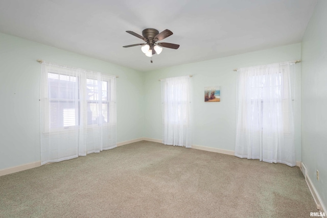 carpeted spare room featuring a ceiling fan and baseboards