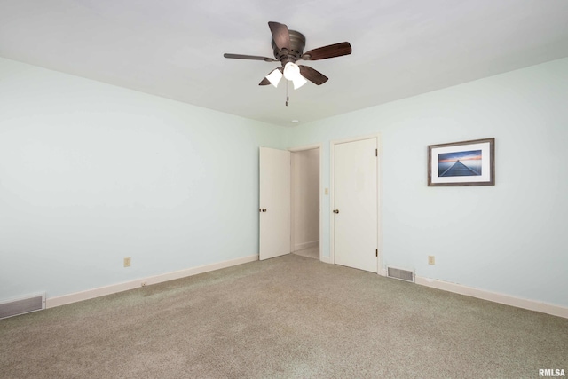 carpeted empty room featuring a ceiling fan, visible vents, and baseboards