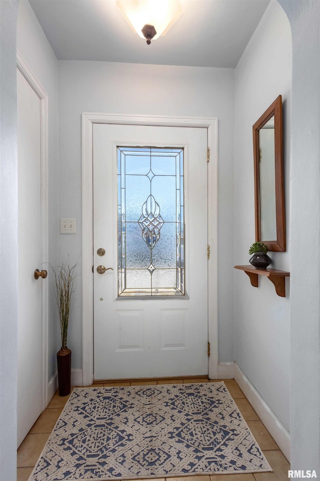 doorway to outside featuring light tile patterned floors, arched walkways, and baseboards